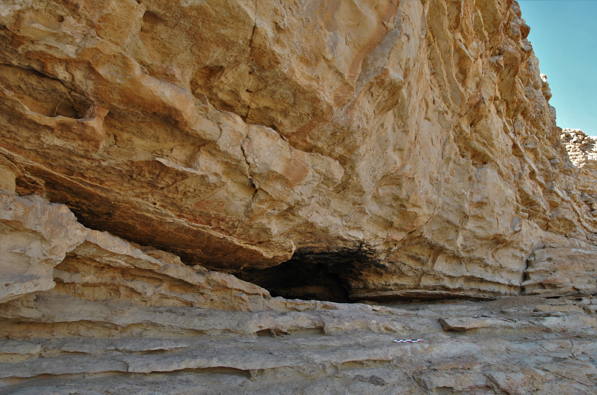 The cliff-face and rock shelter within the central enclave on the western flank of Qarn bint Sa’ud and views across the arid landscapes